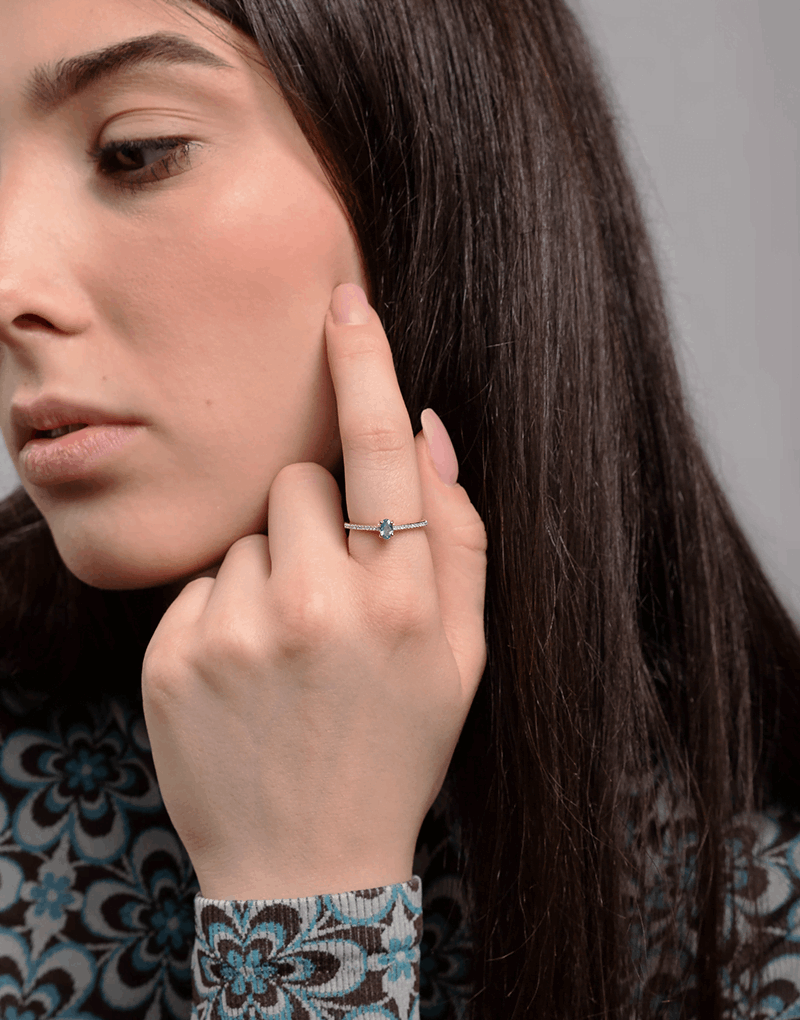 Stylowy pierścionek z niebieskim topazem i brylantami noszony na dłoni modelki