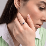 Elegancki pierścionek z szafirem i brylantami noszony przez kobietę w zielonej kamizelce