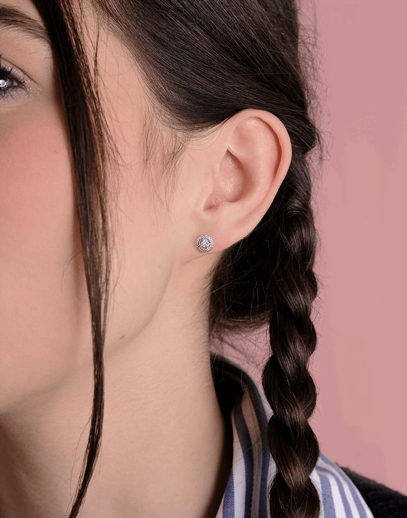 Kolczyki z brylantem złote na uchu modelki z warkoczem, elegancki dodatek biżuteryjny