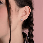 Kolczyki z brylantem złote na uchu modelki z warkoczem, elegancki dodatek biżuteryjny