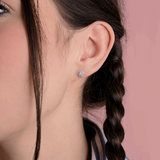 Kolczyki z brylantem złote na uchu modelki z warkoczem, elegancki dodatek biżuteryjny