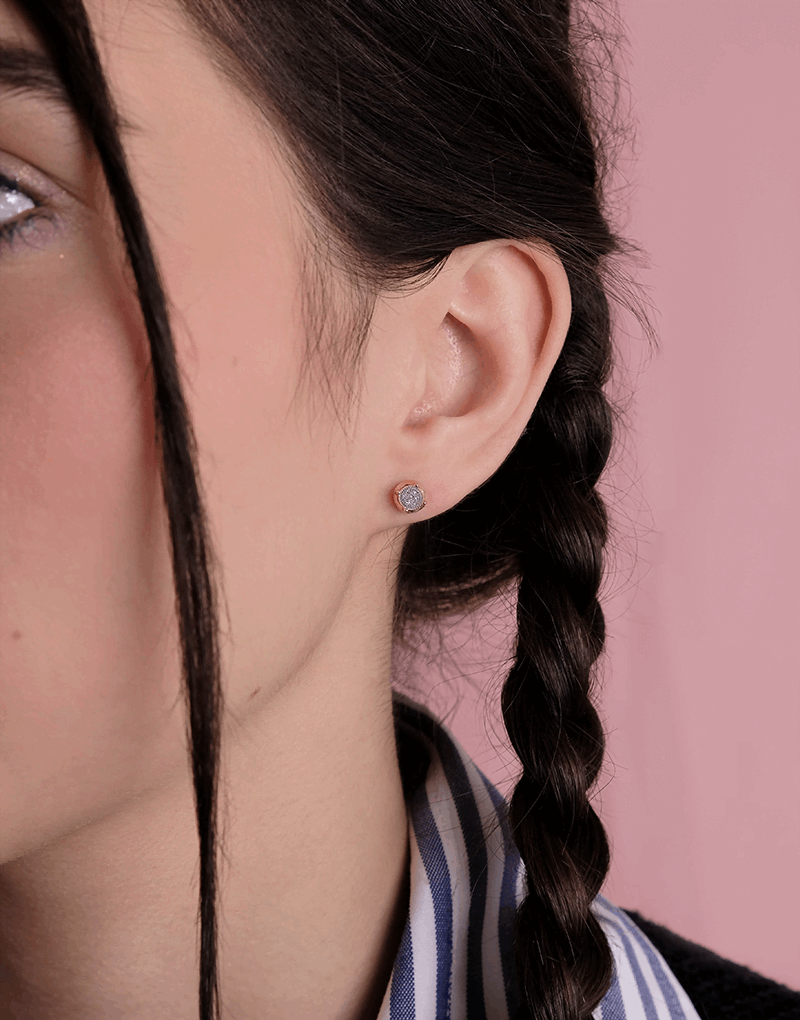 Okrągłe Złote Kolczyki z Brylantami na modelce z warkoczem w tle różowym