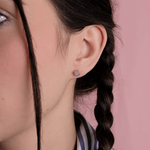 Okrągłe Złote Kolczyki z Brylantami na modelce z warkoczem w tle różowym