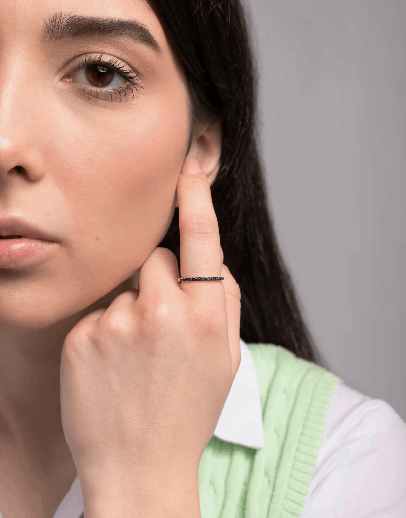 Pierścionek z niebieskim szafirem noszony przez kobietę z delikatnym uśmiechem