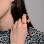 Pierścionek vintage z tanzanitem i brylantami na dłoni modelki, z eleganckim wzorem na bluzce