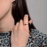 Pierścionek vintage z tanzanitem i brylantami na dłoni modelki, z eleganckim wzorem na bluzce