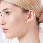 Złote kolczyki z angielskim zapięciem noszone przez kobietę, idealne do codziennych stylizacji.