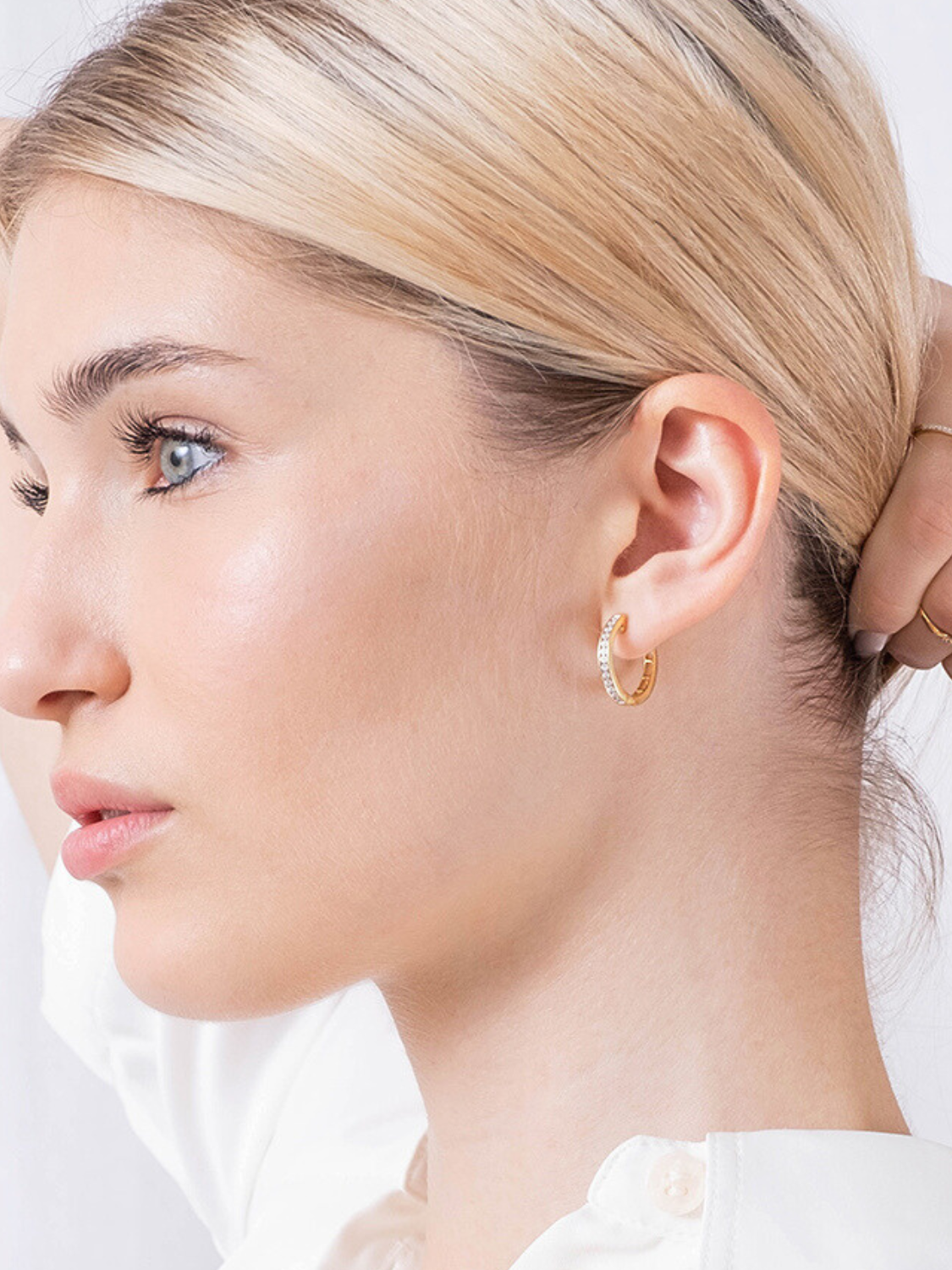 Złote kolczyki z angielskim zapięciem noszone przez kobietę, idealne do codziennych stylizacji.