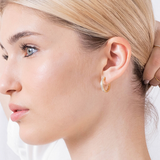 Złote kolczyki z angielskim zapięciem noszone przez kobietę, idealne do codziennych stylizacji.