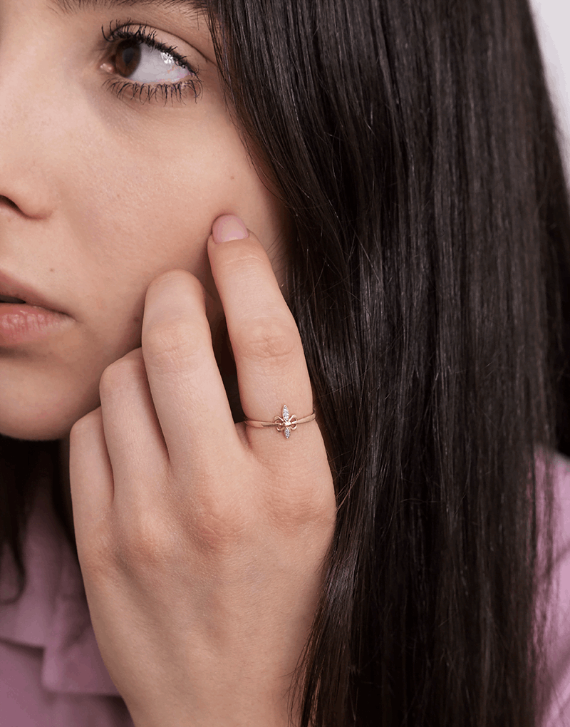 Złoty pierścionek motyl na palcu kobiety z długimi, ciemnymi włosami