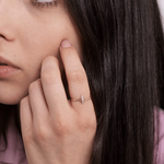 Złoty pierścionek motyl na palcu kobiety z długimi, ciemnymi włosami