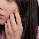 Złoty pierścionek motyl na palcu kobiety z długimi, ciemnymi włosami