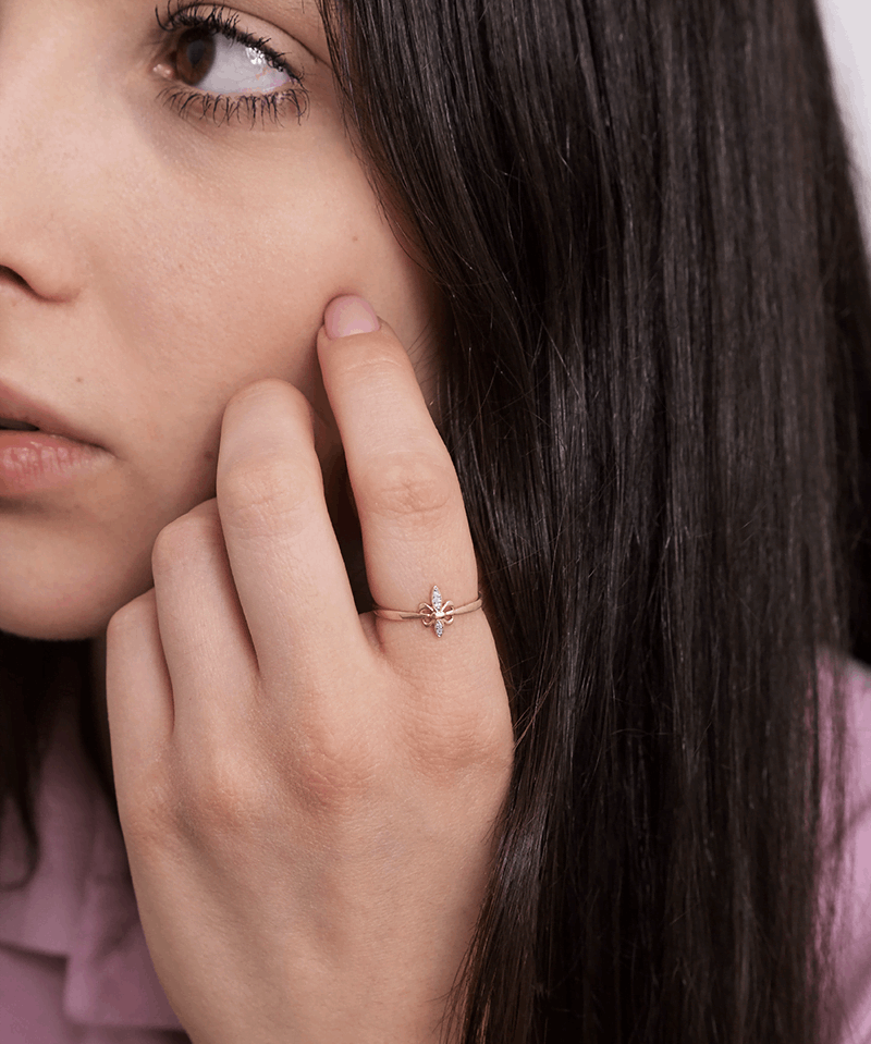 Złoty pierścionek motyl na palcu kobiety z długimi, ciemnymi włosami