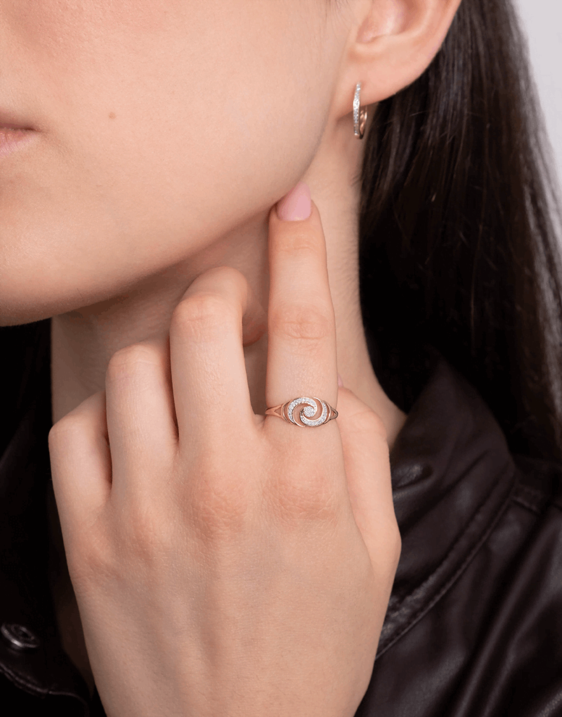 Złoty pierścionek z brylantami w kształcie spirali noszony przez osobę z długimi włosami