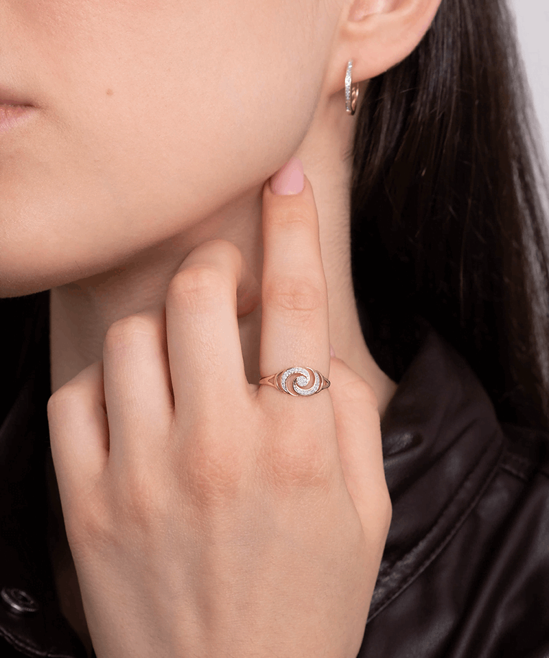 Złoty pierścionek z brylantami w kształcie spirali noszony przez osobę z długimi włosami