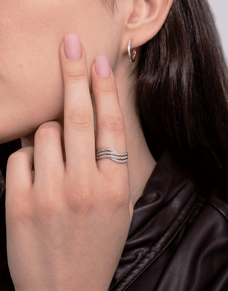 Złoty pierścionek z brylantami na palcu, elegancko prezentujący się na tle stylowej czarnej odzieży.