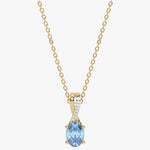 Złoty wisiorek z niebieskim topazem, ozdobiony diamentami na delikatnym łańcuszku.