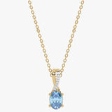 Złoty wisiorek z niebieskim topazem, ozdobiony diamentami na delikatnym łańcuszku.