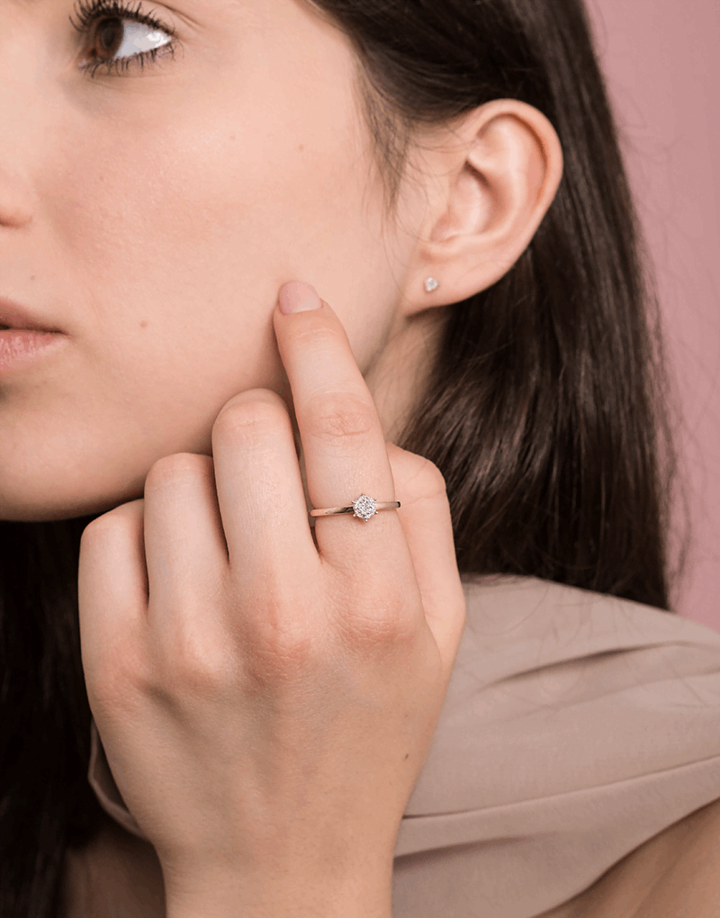 Elegancki pierścionek z brylantami od Venetia Jewels na palcu modelki przy minimalistycznym tle