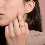 Elegancki pierścionek z brylantami od Venetia Jewels na palcu modelki przy minimalistycznym tle