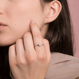 Elegancki pierścionek z brylantami od Venetia Jewels na palcu modelki przy minimalistycznym tle