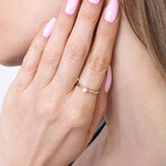 Kobieta nosząca klasyczny pierścionek z brylantem na palcu, w subtelnej stylizacji
