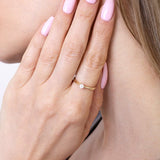 Kobieta nosząca klasyczny pierścionek z brylantem na palcu, w subtelnej stylizacji