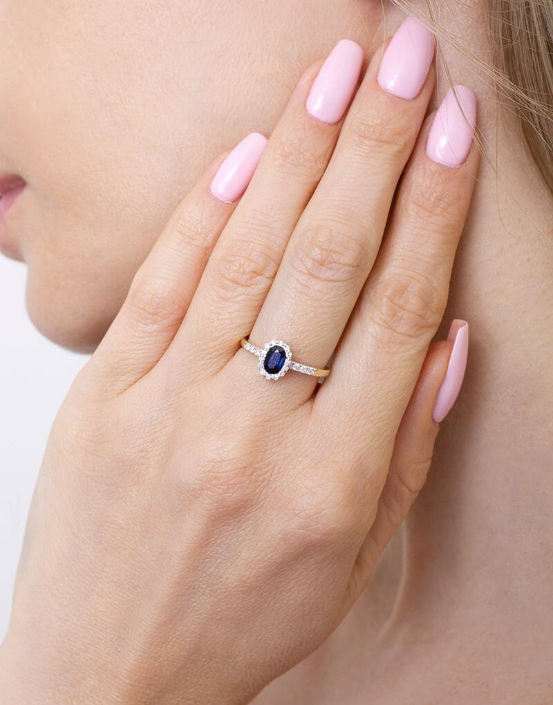 Elegancki pierścionek z niebieskim szafirem i ozdobnymi diamentami na delikatnej złotej obrączce