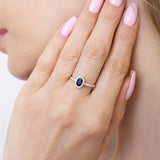 Elegancki pierścionek z niebieskim szafirem i ozdobnymi diamentami na delikatnej złotej obrączce