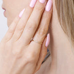 Stylowa smukła obrączka z brylantami noszona na palcu z różowymi paznokciami