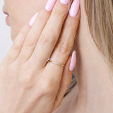 Stylowa smukła obrączka z brylantami noszona na palcu z różowymi paznokciami