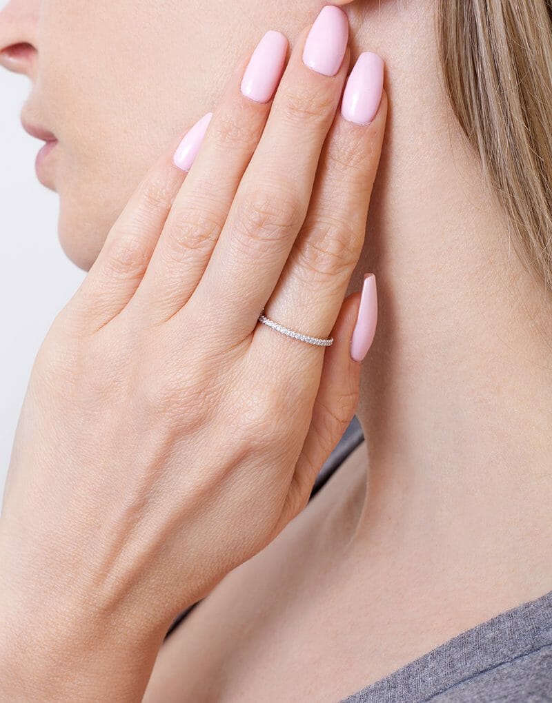 Złota Obrączka z brylantami na palcu modelki z delikatnymi paznokciami w pastelowym kolorze