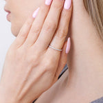 Złota Obrączka z brylantami na palcu modelki z delikatnymi paznokciami w pastelowym kolorze