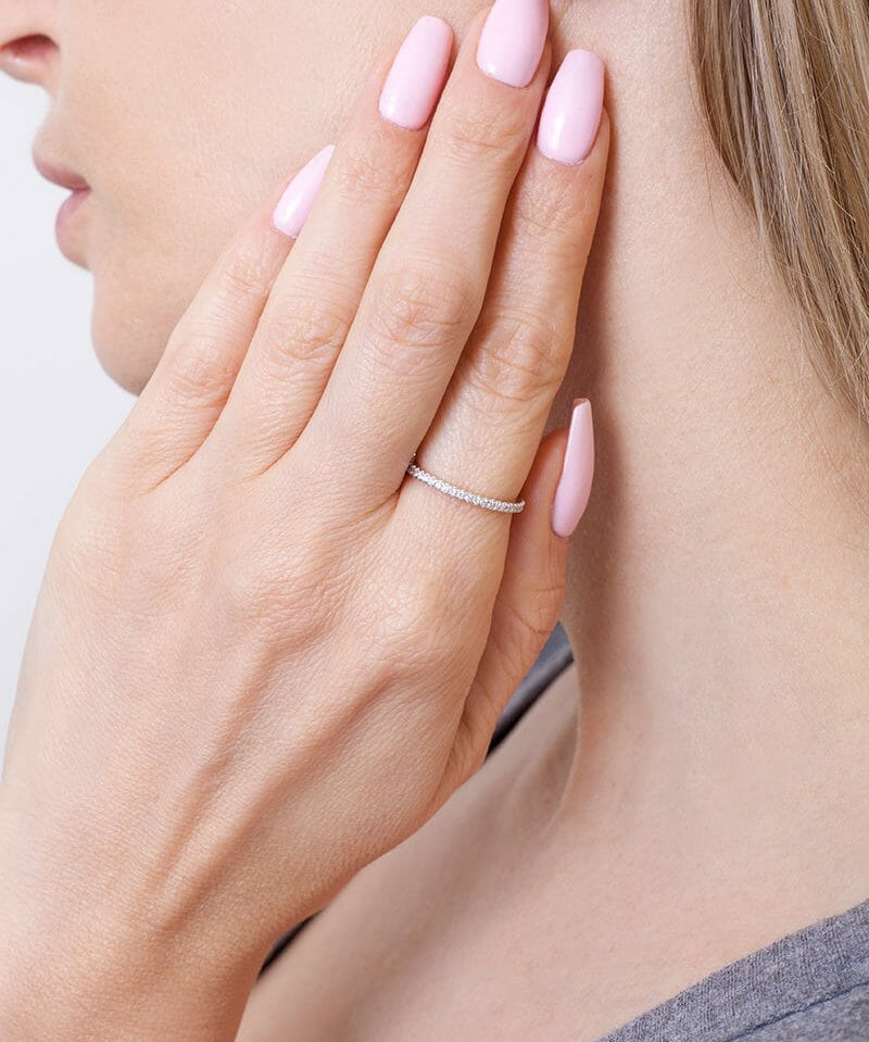 Złota Obrączka z brylantami na palcu modelki z delikatnymi paznokciami w pastelowym kolorze