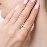 Złota obrączka z brylantami na palcu, pięknie zdobiąca dłoń kobiety z różowymi paznokciami