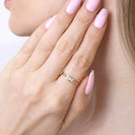 Skręcony złoty pierścionek od Venetia Jewels na dłoni z różowymi paznokciami