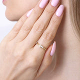 Skręcony złoty pierścionek od Venetia Jewels na dłoni z różowymi paznokciami