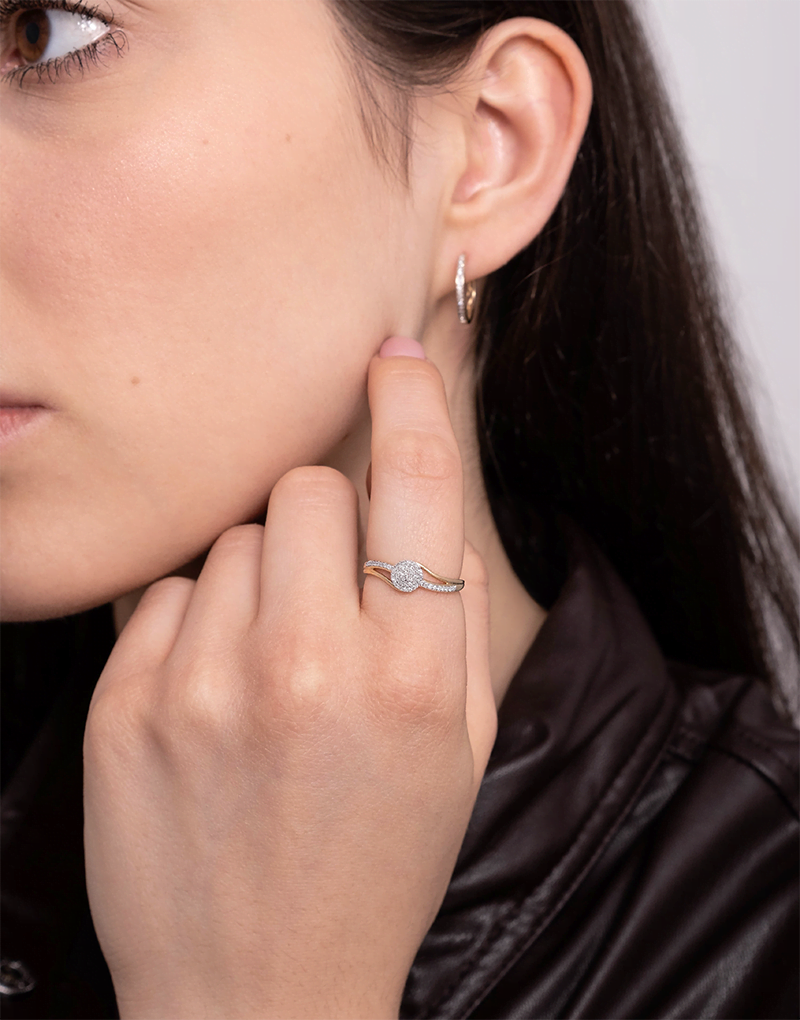 Złoty pierścionek z brylantami na palcu modelki z delikatnym uśmiechem