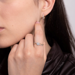 Złoty pierścionek z brylantami na palcu modelki z delikatnym uśmiechem