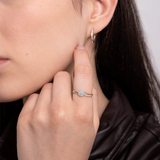 Złoty pierścionek z brylantami na palcu modelki z delikatnym uśmiechem