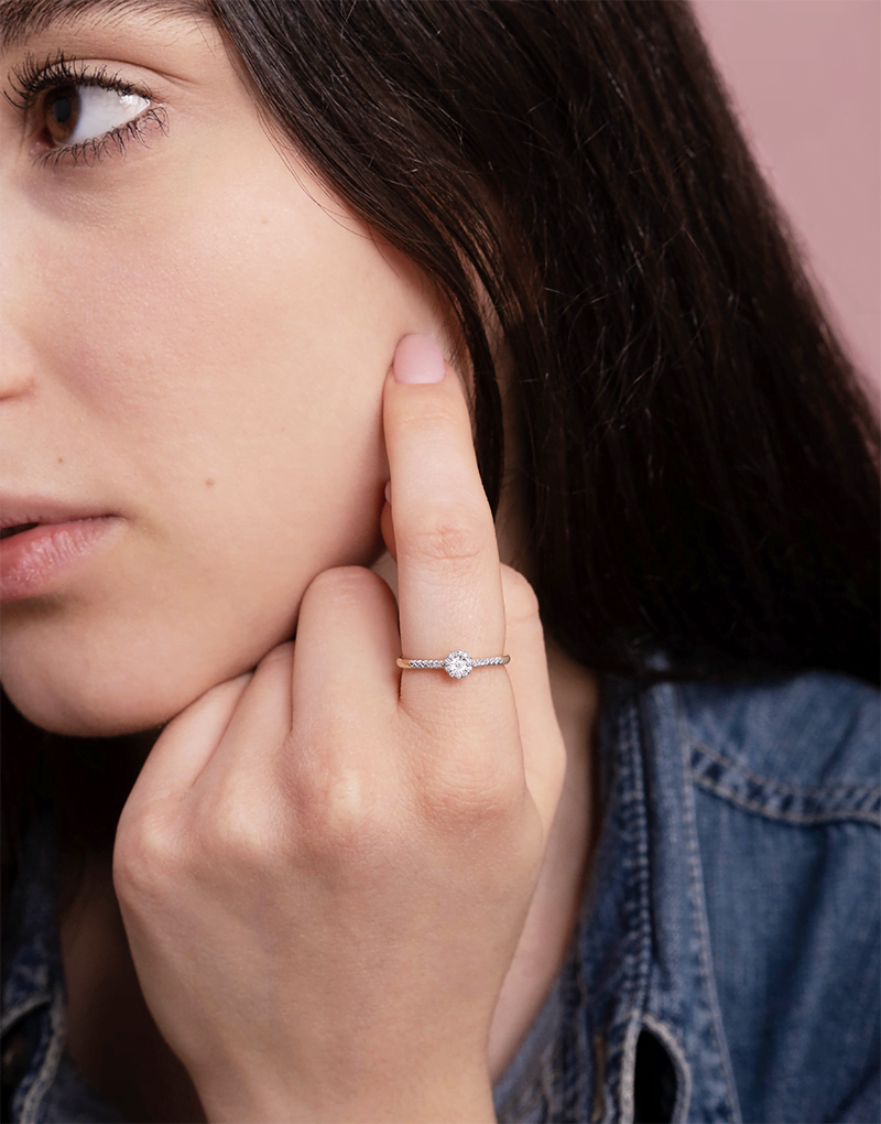 Złoty pierścionek z brylantami noszony na palcu, w stylowej scenerii