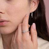 Elegancki Złoty Pierścionek z Brylantami na palcu kobiety, w połączeniu z kolczykami na tle różowym