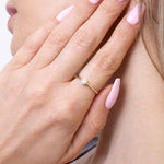 Złoty pierścionek z brylantem na delikatnym palcu z różowymi paznokciami