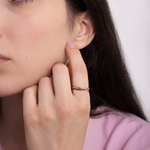 Złoty pierścionek z szafirami na palcu modelki w bluzce różowej