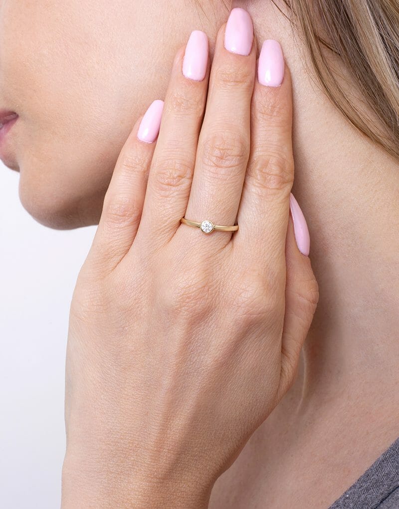 Złoty pierścionek zaręczynowy z brylantem noszony na palcu, subtelny i elegancki design