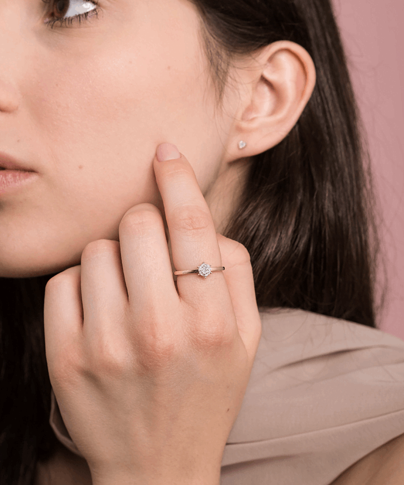 Elegancki pierścionek z brylantami od Venetia Jewels na palcu modelki przy minimalistycznym tle